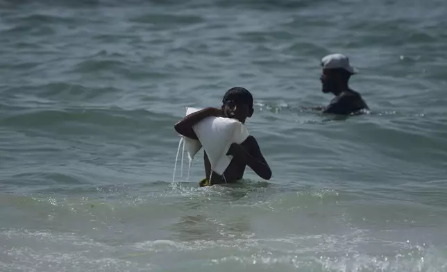 A Palestinian youth carries a sack of aid that landed in the Mediterranean Sea after being airdropped over central Gaza, at the shore of Zawaida, Gaza Strip, July 29, 2025. (AP Photo/Abdel Kareem Hana)