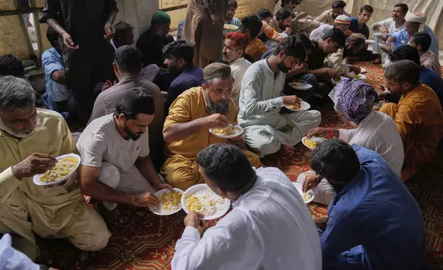 Devotees eat food during celebrations of the three-day annual festival or 'Urs' of famous saint Hazrat Ali Hajveri, popularly known as Data Ganj Bakhsh at his shrine, in Lahore, Pakistan, Friday, Aug. 15, 2025. (AP Photo/K.M. Chaudary)