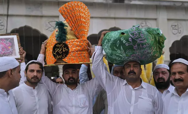 Devotees carry a big turban and bundle of garland as they arrive to attend celebrations of the three-day annual festival or 'Urs' of famous saint Hazrat Ali Hajveri, popularly known as Data Ganj Bakhsh at his shrine, in Lahore, Pakistan, Friday, Aug. 15, 2025. (AP Photo/K.M. Chaudary)