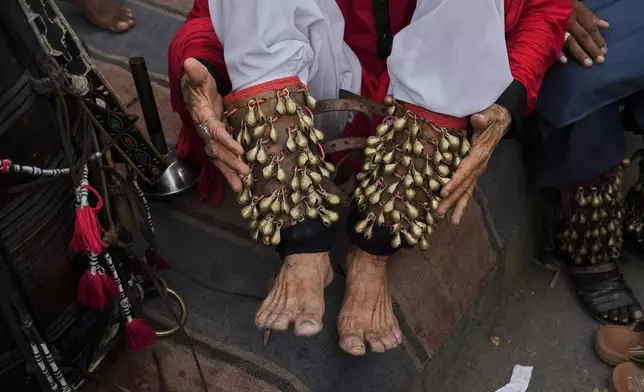 A spiritual path devotee locally called 'Malang' ties 'Ghungroo', a set of small metallic bells strung together, on his feet for performing a devotional dance called 'Dhamaal' during the celebrations of the three-day annual festival or 'Urs' of famous saint Hazrat Ali Hajveri, popularly known as Data Ganj Bakhsh at his shrine, in Lahore, Pakistan, Wednesday, Aug. 13, 2025. (AP Photo/K.M. Chaudary)