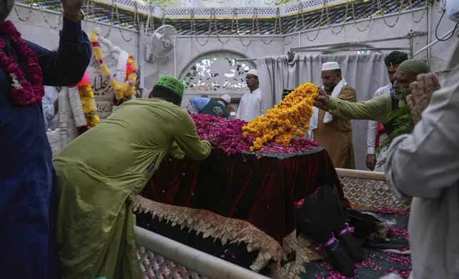 Devotees lay garland and ceremonial cloth locally called 'chaddar' on the shrine of famous saint Hazrat Ali Hajveri, popularly known as Data Ganj Bakhsh during the celebrations of the three-day annual festival or 'Urs' at his shrine, in Lahore, Pakistan, Thursday, Aug. 14, 2025. (AP Photo/K.M. Chaudary)