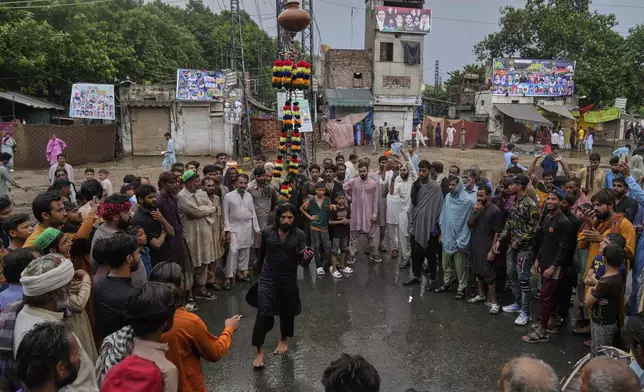 Devotees look a performer balancing clay pot with a iron structure on his head as they attend the celebrations of the three-day annual festival or 'Urs' of famous saint Hazrat Ali Hajveri, popularly known as Data Ganj Bakhsh at his shrine, in Lahore, Pakistan, Wednesday, Aug. 13, 2025. (AP Photo/K.M. Chaudary)