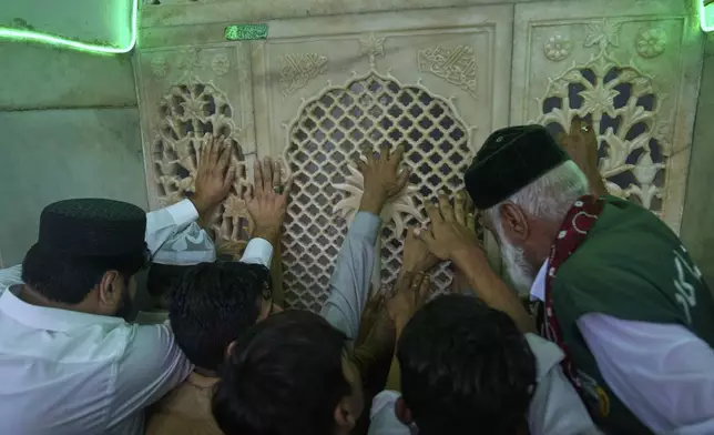 Devotees touches shrine's lattice as a faithfulness as they attending celebrations of the three-day annual festival or 'Urs' of famous saint Hazrat Ali Hajveri, popularly known as Data Ganj Bakhsh at his shrine, in Lahore, Pakistan, Thursday, Aug. 14, 2025. (AP Photo/K.M. Chaudary)