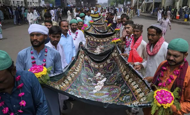 Devotees arrive with ceremonial cloth locally called 'chaddar' painted with 'Quranic recitations' which they place over the saint's grave during the celebrations of the three-day annual festival or 'Urs' of famous saint Hazrat Ali Hajveri, popularly known as Data Ganj Bakhsh at his shrine, in Lahore, Pakistan, Friday, Aug. 15, 2025. (AP Photo/K.M. Chaudary)