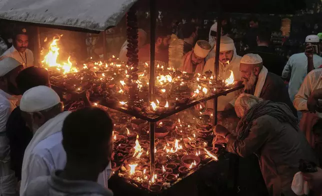 Devotees light clay-lamp during the celebrations of the three-day annual festival or 'Urs' of famous saint Hazrat Ali Hajveri, popularly known as Data Ganj Bakhsh at his shrine, in Lahore, Pakistan, Wednesday, Aug. 13, 2025. (AP Photo/K.M. Chaudary)