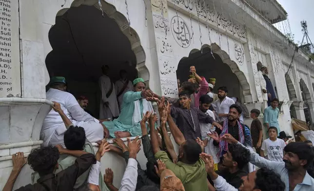 Devotees jostle to get free sweets as they attending celebrations of the three-day annual festival or 'Urs' of famous saint Hazrat Ali Hajveri, popularly known as Data Ganj Bakhsh at his shrine, in Lahore, Pakistan, Thursday, Aug. 14, 2025. (AP Photo/K.M. Chaudary)