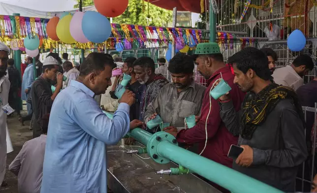 Devotees drink milk at a stall as they attending celebrations of the three-day annual festival or 'Urs' of famous saint Hazrat Ali Hajveri, popularly known as Data Ganj Bakhsh at his shrine, in Lahore, Pakistan, Wednesday, Aug. 13, 2025. (AP Photo/K.M. Chaudary)