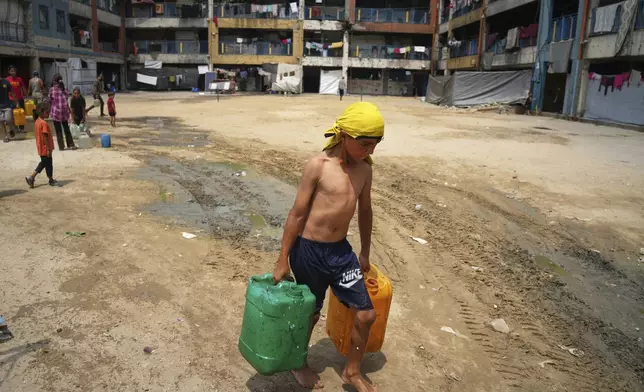 In the summer heat, a Palestinian boy carries jerrycans after collecting water from a distribution point in Gaza City, Tuesday, Aug. 12, 2025. (AP Photo/Jehad Alshrafi)
