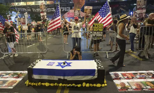 Einav Zangauker, center, mother of Matan Zangauker who is held hostage by Hamas, sits beside an installation resembling a coffin during a protest demanding an end to the war and the immediate release of hostages held by Hamas in the Gaza Strip, in Tel Aviv, Israel, Tuesday, Aug. 12, 2025. (AP Photo/Ariel Schalit)