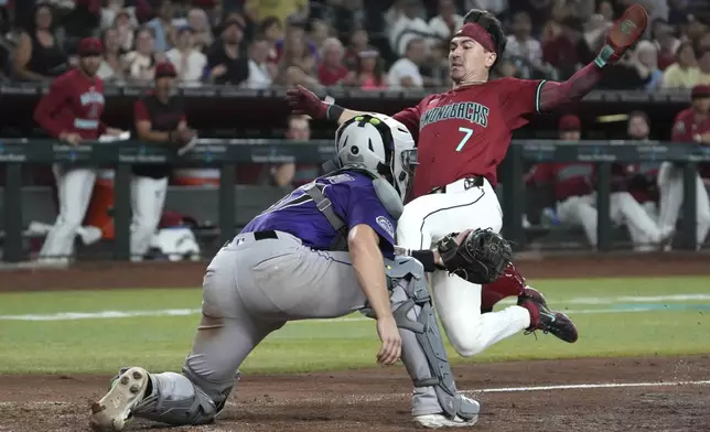 Arizona Diamondbacks' Corbin Carroll, right, leaps to score against Colorado Rockies catcher Braxton Fulford, left, after a single hit by Ketel Marte in the fifth inning of a baseball game, Sunday, Aug 10, 2025, in Phoenix. (AP Photo/Rick Scuteri)