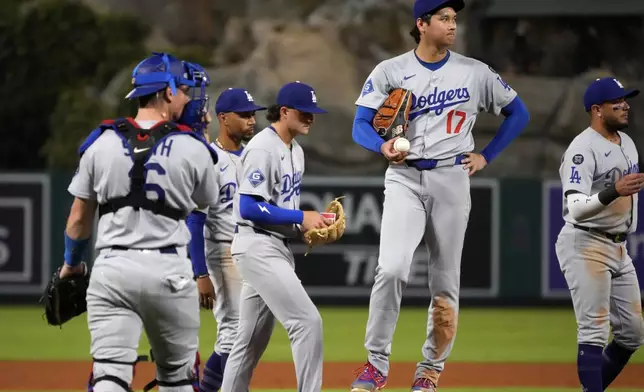 Los Angeles Dodgers starting pitcher Shohei Ohtani, second from right, waits to be taken out of the game throws to the plate during the fifth inning of a baseball game against the Los Angeles Angels, Wednesday, Aug. 13, 2025, in Anaheim, Calif. (AP Photo/Mark J. Terrill)