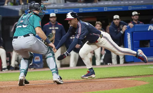 Cleveland Guardians' Brayan Rocchio, right, begins his slide into home plate for the winning run as Seattle Mariners' Cal Raleigh waits for the throw during the ninth inning of a baseball game, Friday, Aug. 29, 2025, in Cleveland. (AP Photo/Phil Long)