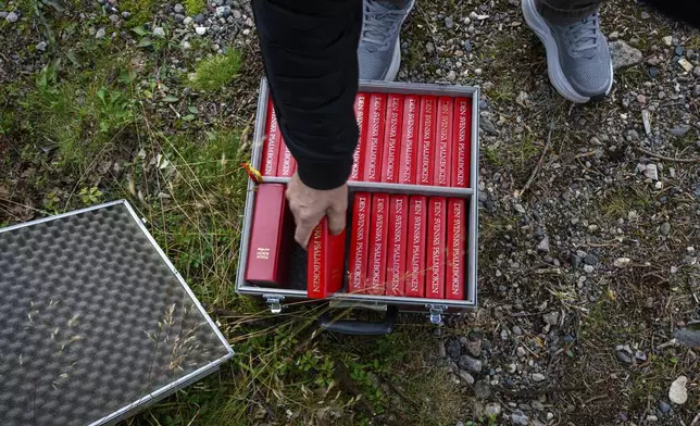A person handles a hymnal during an outdoor prayer for the move of the Kiruna Church, a Sami style wooden Swedish Lutheran church, called Kiruna Kyrka in Swedish, in Kiruna, Sweden, Sunday, Aug. 17, 2025, two days before its move along a 5-kilometer (3-mile) route east to a new city center as part of the town's relocation. (AP Photo/Malin Haarala)