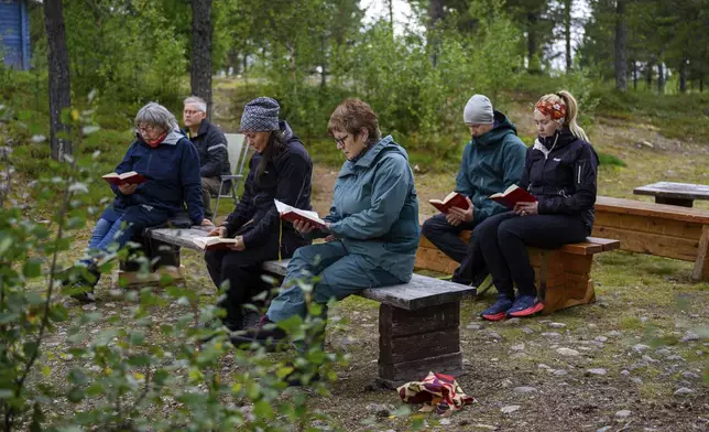 People hold an outdoor prayer for the move of the Kiruna Church, a Sami style wooden Swedish Lutheran church, called Kiruna Kyrka in Swedish, in Kiruna, Sweden, Sunday, Aug. 17, 2025, two days before its move along a 5-kilometer (3-mile) route east to a new city center as part of the town's relocation. (AP Photo/Malin Haarala)