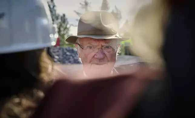 Sweden's King Carl XVI Gustaf speaks to media next to the Kiruna Church, a Sami style wooden Swedish Lutheran church, called Kiruna Kyrka in Swedish, in Kiruna, Sweden, Wednesday, Aug. 20, 2025, after the completion of its move along a 5-km. (3-mile) route east to a new city center as part of the town's relocation.(AP Photo/Malin Haarala)