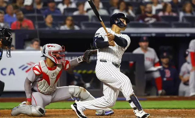 New York Yankees' Trent Grisham, right, follows through on a home run during the fifth inning of a baseball game against the Boston Red Sox, Sunday, Aug. 24, 2025, in New York. (AP Photo/Noah K. Murray)