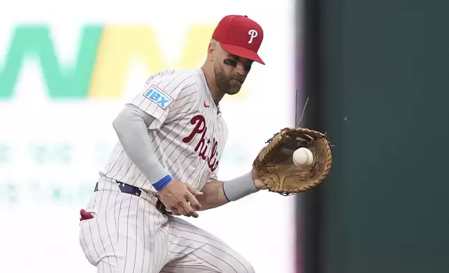 Philadelphia Phillies first base Bryce Harper fields a ball hit by Baltimore Orioles' Jackson Holliday during the first inning of a baseball game, Tuesday, Aug. 5, 2025, in Philadelphia. (AP Photo/Matt Rourke)