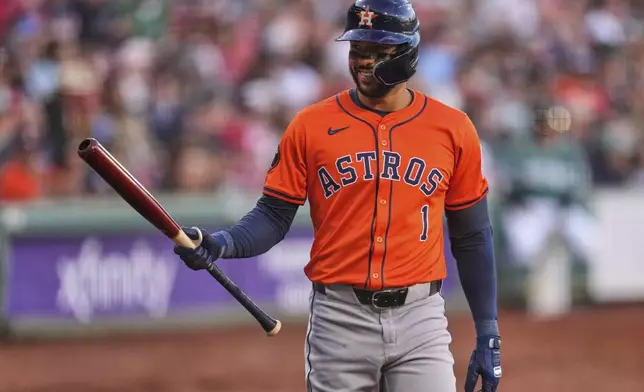 Houston Astros designated hitter Carlos Correa raises his bat while greeted by fans during the first inning of a baseball game against the Boston Red Sox at Fenway Park, Friday, Aug. 1, 2025, in Boston. (AP Photo/Charles Krupa)