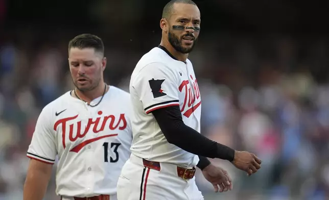 Minnesota Twins' Carlos Correa, right, walks across the field near Ty France (13) after hitting a lineout to third base to end the bottom of the third inning of a baseball game against the Washington Nationals, Saturday, July 26, 2025, in Minneapolis. (AP Photo/Abbie Parr)