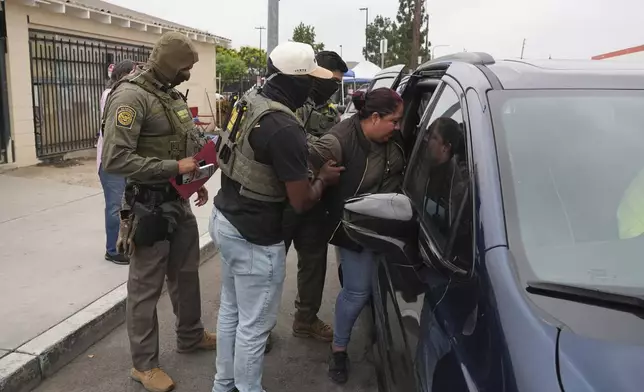 A woman is detained by U.S. Border Patrol agents outside a Home Depot Friday, Aug. 15, 2025, in Los Angeles. (AP Photo/Gregory Bull)