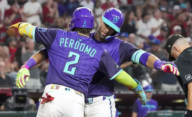 Arizona Diamondbacks' Geraldo Perdomo (2) gives Lourdes Gurriel Jr., right, a hug after Gurriel Jr. hit a home run against the Cincinnati Reds during the third inning of a baseball game Saturday, Aug. 23, 2025, in Phoenix. (AP Photo/Darryl Webb)