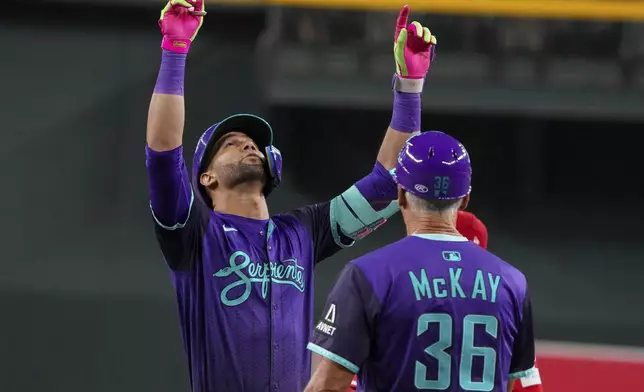 Arizona Diamondbacks first base coach Dave McKay (36) watches as Lourdes Gurriel Jr., left, points skyward after knocking in a run against the Cincinnati Reds during the first inning of a baseball game Saturday, Aug. 23, 2025, in Phoenix. (AP Photo/Darryl Webb)