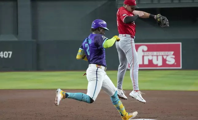 Arizona Diamondbacks' Geraldo Perdomo, left, beats the throw to first base after Cincinnati Reds first base Spencer Steer had to jump for the throw during the third inning of a baseball game Saturday, Aug. 23, 2025, in Phoenix. (AP Photo/Darryl Webb)