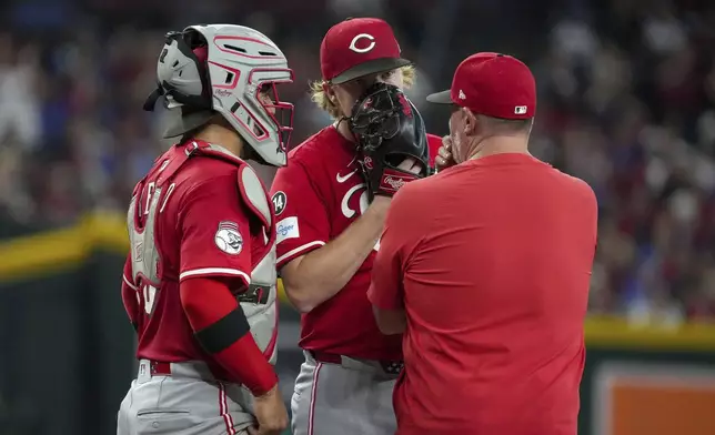 Cincinnati Reds pitcher Andrew Abbott, center, talks with catcher Jose Trevino, left, and pitching Derek Johnson, right, after giving up three runs to the the Arizona Diamondbacks during the first inning of a baseball game Saturday, Aug. 23, 2025, in Phoenix. (AP Photo/Darryl Webb)