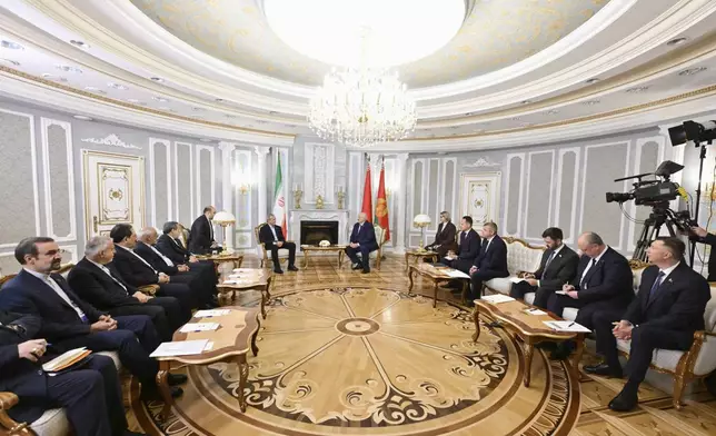 In this photo, released by Belarusian Presidential Press Service, Belarusian President Alexander Lukashenko, background right, and Iranian President Masoud Pezeshkian, background left, talk to each other during their meeting in Minsk, Belarus, Wednesday, Aug. 20, 2025. (Belarusian Presidential Press Service via AP)