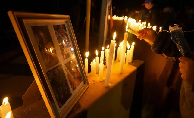 A person lights a candle during a vigil in front of El Teniente copper mine, operated by Codelco, where a cave-in killed one worker and trapped five others underground, halting operations in Rancagua, Chile, Saturday, Aug. 2, 2025. (AP Photo/Esteban Felix)