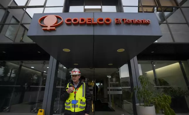 A worker stands at an entrance of an office of Codelco, the company that operates the El Teniente copper mine, where a cave-in killed one worker and trapped five others underground, halting operations in Rancagua, Chile, Saturday, Aug. 2, 2025. (AP Photo/Esteban Felix)