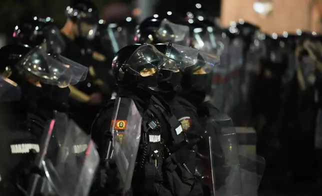 A Serbian gendarmerie officer with a sticker depicting Jesus Christ stands in cordon separating protesters from opposing camps during an anti-government protest in Belgrade, Serbia, Wednesday, Aug. 13, 2025. (AP Photo/Darko Vojinovic)