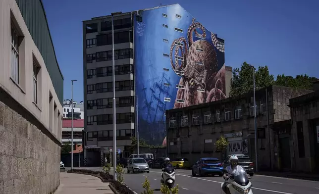Vehicles move down a street with an octopus mural in the background Thursday, June 26, 2025, in Vigo, Spain. (AP Photo/Annika Hammerschlag)