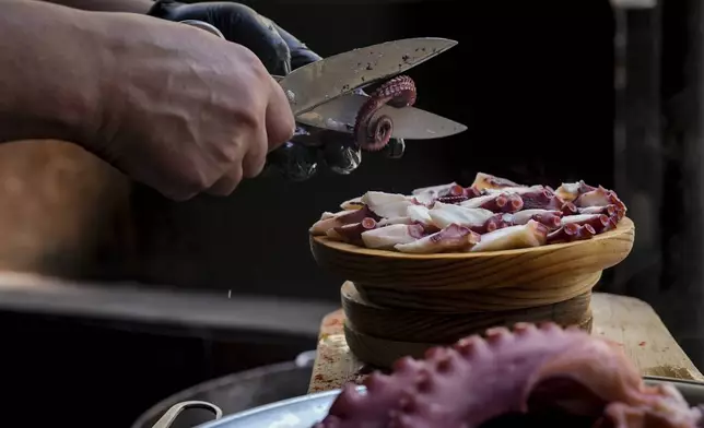 Octopus is prepared at a restaurant on Wednesday, June 25, 2025, in O Carballino, Spain. (AP Photo/Annika Hammerschlag)
