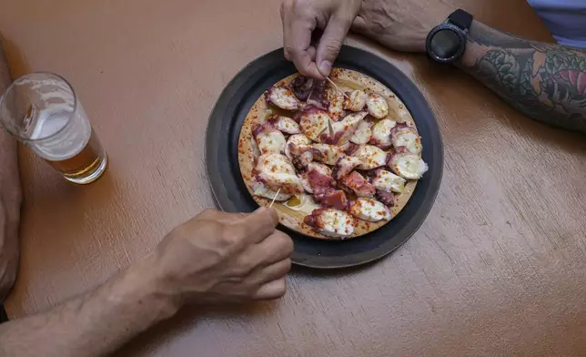 Diners snack on octopus at Casa Gazpara on Wednesday, June 25, 2025, in O Carballino, Spain. (AP Photo/Annika Hammerschlag)