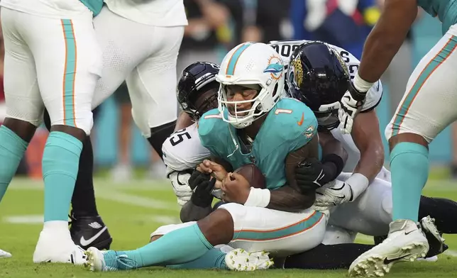 Miami Dolphins quarterback Tua Tagovailoa (1) falls on the field after he was sacked by Jacksonville Jaguars defensive end BJ Green II (95) during the first half of an NFL preseason football game, Saturday, Aug. 23, 2025, in Miami Gardens, Fla. (AP Photo/Rebecca Blackwell)