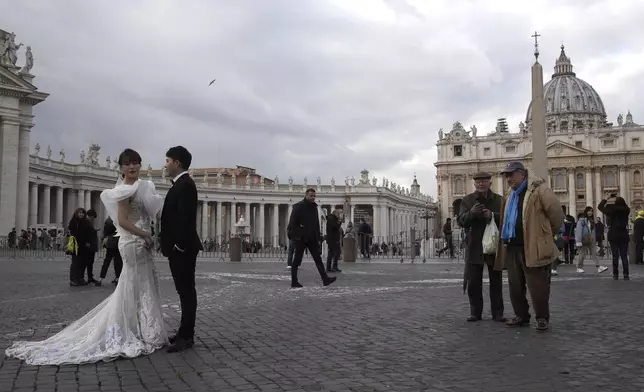 FILE - People look at Chinese couple in wedding clothes posing for photos in front of St. Peter's Square at the Vatican, Jan. 17, 2019. (AP Photo/Alessandra Tarantino, File)