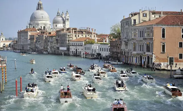 FILE - The boat carrying George Clooney and his wife, Amal Alamuddin, is surrounded by media and security boats as they cruise the Grand Canal after leaving the Aman luxury Hotel in Venice, Italy, Sept. 28, 2014. (AP Photo/Luigi Costantini, File)