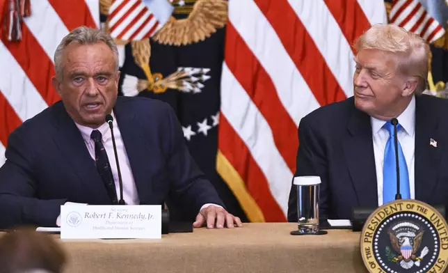 Health and Human Service Secretary Robert F. Kennedy, Jr., left, speaks at an event in the East Room of the White House, Wednesday, July 30, 2025, in Washington, as President Donald Trump, looks on. (AP Photo/John McDonnell)