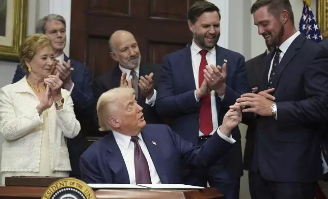 President Donald Trump hands a pen to professional golfer Bryson DeChambeau after Trump signed an executive order restarting the Presidential Fitness Test in public schools as Secretary of Education Linda McMahon, from left, Treasury Secretary Scott Bessent, Commerce Secretary Howard Lutnick and Vice President JD Vance watch, Thursday, July 31, 2025, in the Roosevelt Room of the White House in Washington. (AP Photo/Jacquelyn Martin)