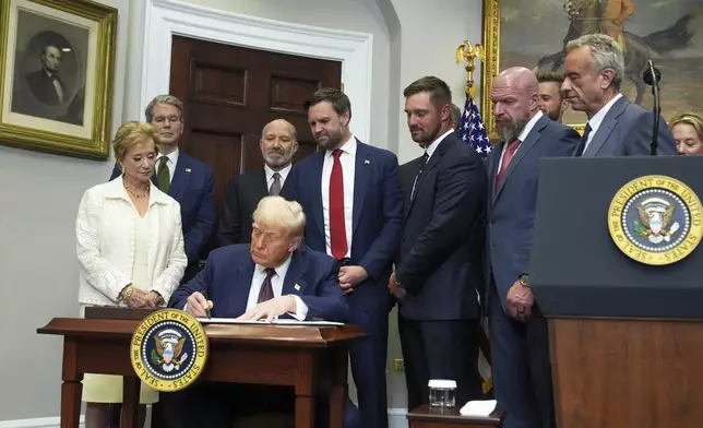 President Donald Trump signs an executive order restarting the Presidential Fitness Test in public schools as Secretary of Education Linda McMahon, from left, Treasury Secretary Scott Bessent, Commerce Secretary Howard Lutnick, Vice President JD Vance, professional golfer Bryson DeChambeau, WWE CCO Triple H and Health and Human Services Secretary Robert F. Kennedy Jr. watch, Thursday, July 31, 2025, in the Roosevelt Room of the White House in Washington. (AP Photo/Jacquelyn Martin)