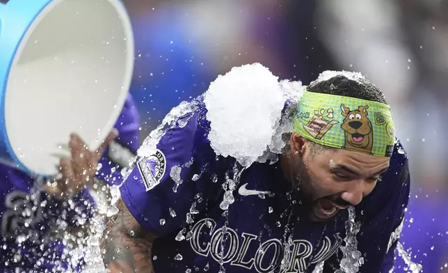 Colorado Rockies' Warming Bernabel, right, is doused by teammate Jordan Beck, back left, after hitting a walk-off RBI single off Los Angeles Dodgers relief pitcher Justin Wrobleski in the ninth inning of a baseball game Monday, Aug. 18, 2025, in Denver. (AP Photo/David Zalubowski)
