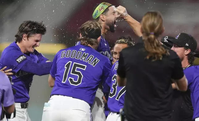 Teammates surround Colorado Rockies' Warming Bernabel, center top, to celebrate after his walk-off RBI single off Los Angeles Dodgers relief pitcher Justin Wrobleski in the ninth inning of a baseball game Monday, Aug. 18, 2025, in Denver. (AP Photo/David Zalubowski)