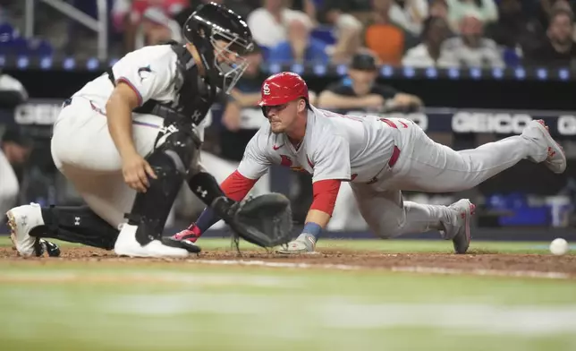 St. Louis Cardinals' Nolan Gorman, right, beats the throw to score on a single by Pedro Pages during the eighth inning of a baseball game against the Miami Marlins, Monday, Aug. 18, 2025, in Miami. (AP Photo/Lynne Sladky)