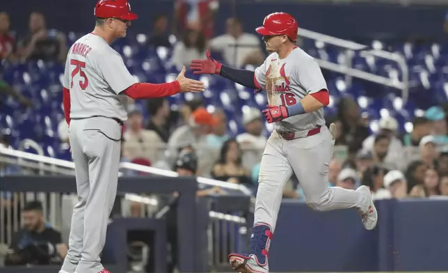 St. Louis Cardinals' Nolan Gorman (16) shakes hands with third base coach Ron Warner (73) after hitting a two run home run during the ninth inning of a baseball game against the Miami Marlins, Monday, Aug. 18, 2025, in Miami. (AP Photo/Lynne Sladky)