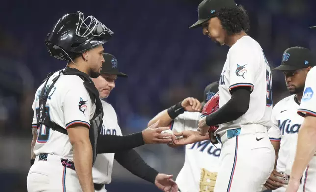 Miami Marlins starting pitcher Eury Perez, right, hands the ball to manager Clayton McCullough, left, after being relieved during the fifth inning of a baseball game against the St. Louis Cardinals, Monday, Aug. 18, 2025, in Miami. (AP Photo/Lynne Sladky)