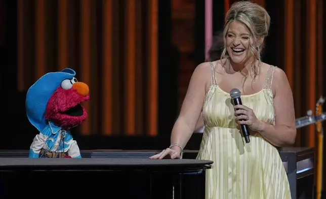 Sesame Street's Elmo, left, performs with Lauren Alaina at the Grand Ole Opry, Thursday, Aug. 14, 2025, in Nashville, Tenn. (AP Photo/George Walker IV)