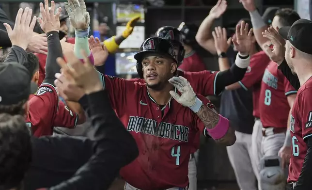 Arizona Diamondbacks' Ketel Marte celebrates in the dugout with the team after hitting a three-run home run in the ninth inning of a baseball game against the Texas Rangers Wednesday, Aug. 13, 2025, in Arlington, Texas. (AP Photo/Tony Gutierrez)