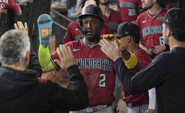 Arizona Diamondbacks' Geraldo Perdomo celebrates with the team after scoring on a Ketel Marte single in the third inning of a baseball game against the Texas Rangers Wednesday, Aug. 13, 2025, in Arlington, Texas. (AP Photo/Tony Gutierrez)