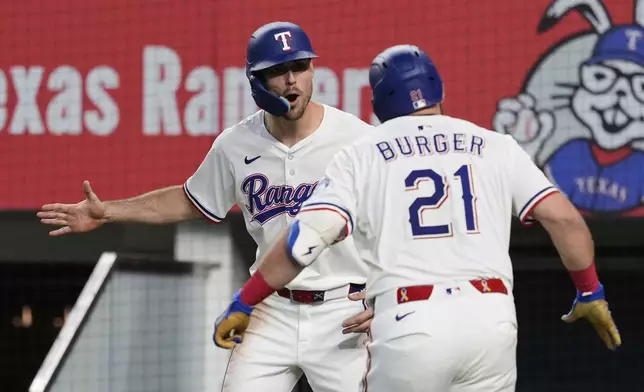 Texas Rangers' Evan Carter, left, and Jake Burger (21) celebrate Burger's two run home run that scored Carter in the fourth inning of a baseball game against the Arizona Diamondbacks Wednesday, Aug. 13, 2025, in Arlington, Texas. (AP Photo/Tony Gutierrez)